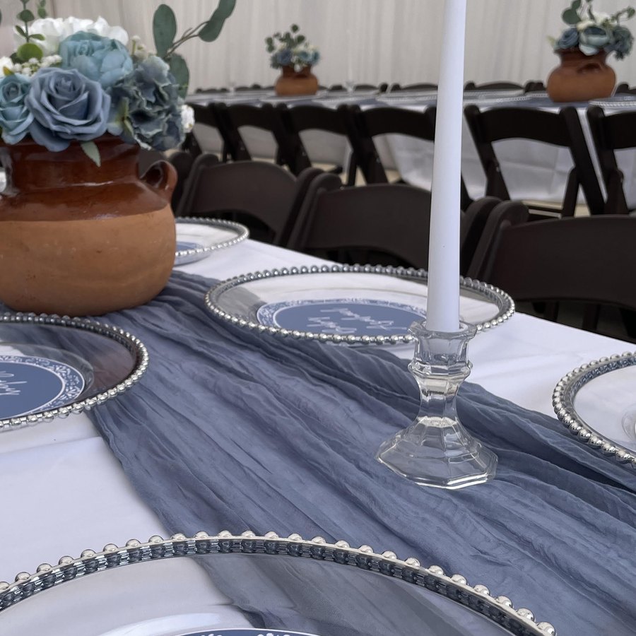 Brown padded folding chair rentals at an elegantly set banquet table with charger plates under a white marquee tent