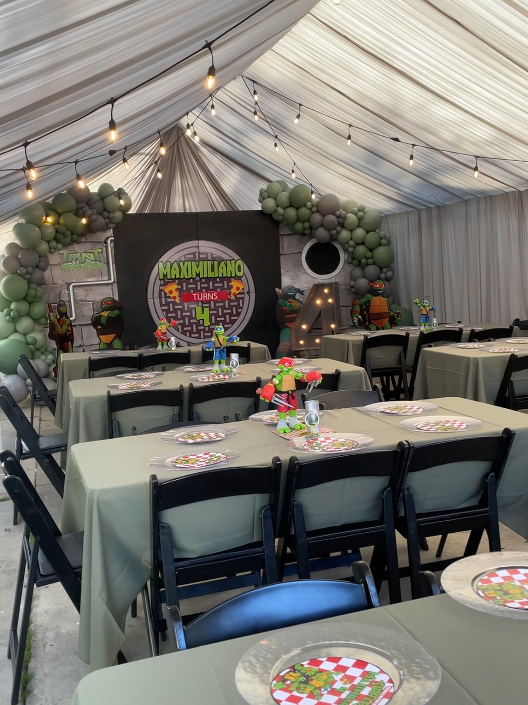 Teenage Mutant Ninja Turtles themed 'Maximiliano Turns 4' birthday with green balloon garlands, string lights and sage table linens
