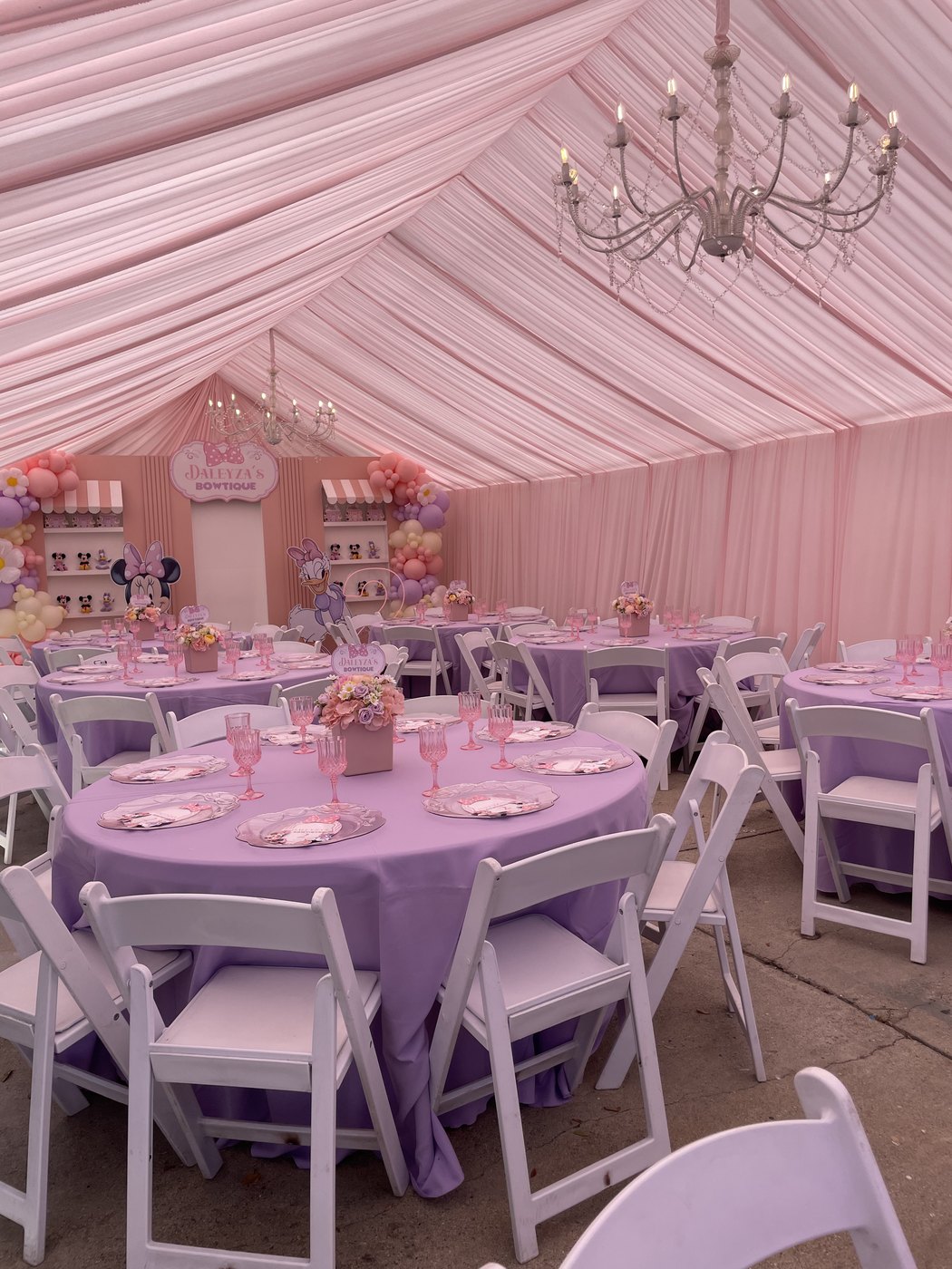 Minnie Mouse 'Daleyza's Bowtique' birthday tent with pink draping, chandeliers, lavender round tables and white folding chairs